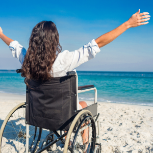 Women in wheelchair in the sunshine on the beach